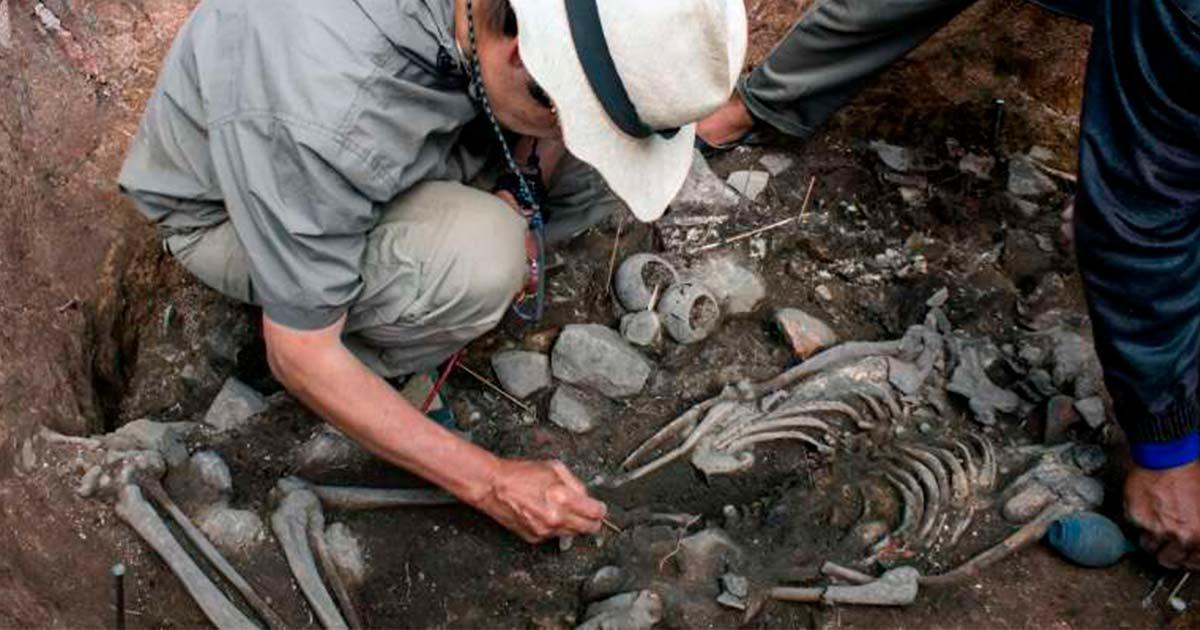 A priest buried face down with small bowls.