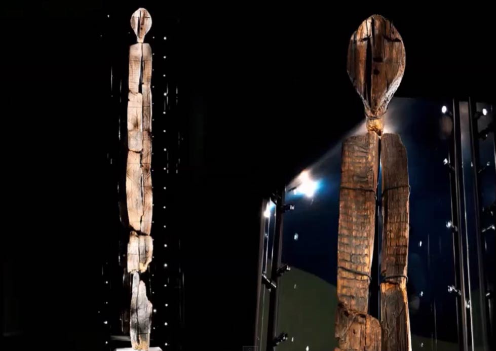 A wooden statue from a peat bog, covered in marks